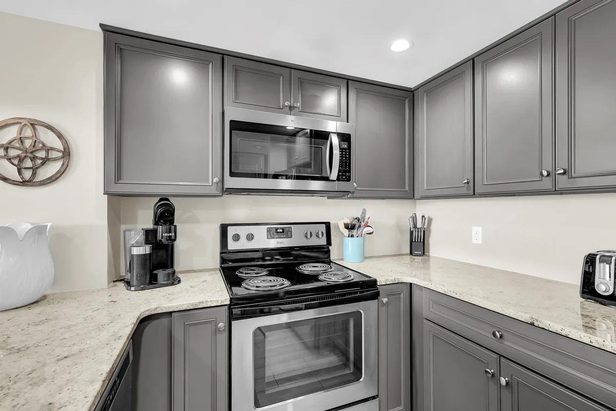 A stylish kitchen corner with gleaming stainless steel appliances, a luxurious granite countertop, and modern decorative wall art. The space is uncluttered and functional, perfect for creative cooking endeavors.