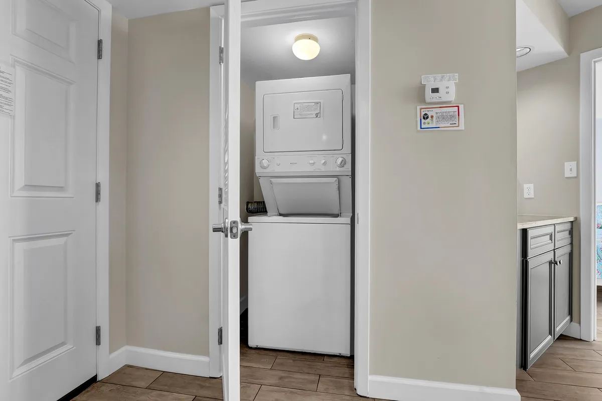 A tidy laundry area featuring a washing machine and dryer, with a doorway leading to another part of the home. The space is clean and efficient, ensuring guests have the convenience of in-unit laundry during their stay.