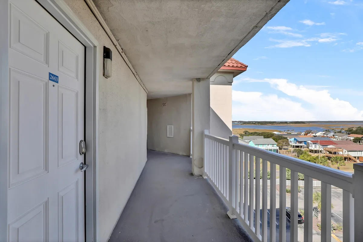 A tranquil exterior view from the property’s balcony, featuring a doorway and railing that overlook a scenic landscape. The setting invites guests to enjoy the outdoors and soak in the peaceful ambiance.