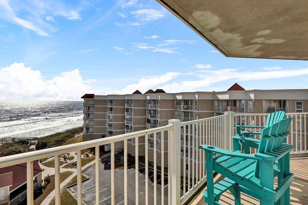 A serene balcony setup with comfortable seating overlooking the endless blue ocean and sky. The vantage point is perfect for sipping morning coffee or unwinding at sunset, with unobstructed water views and clouds enhancing the tranquil mood.