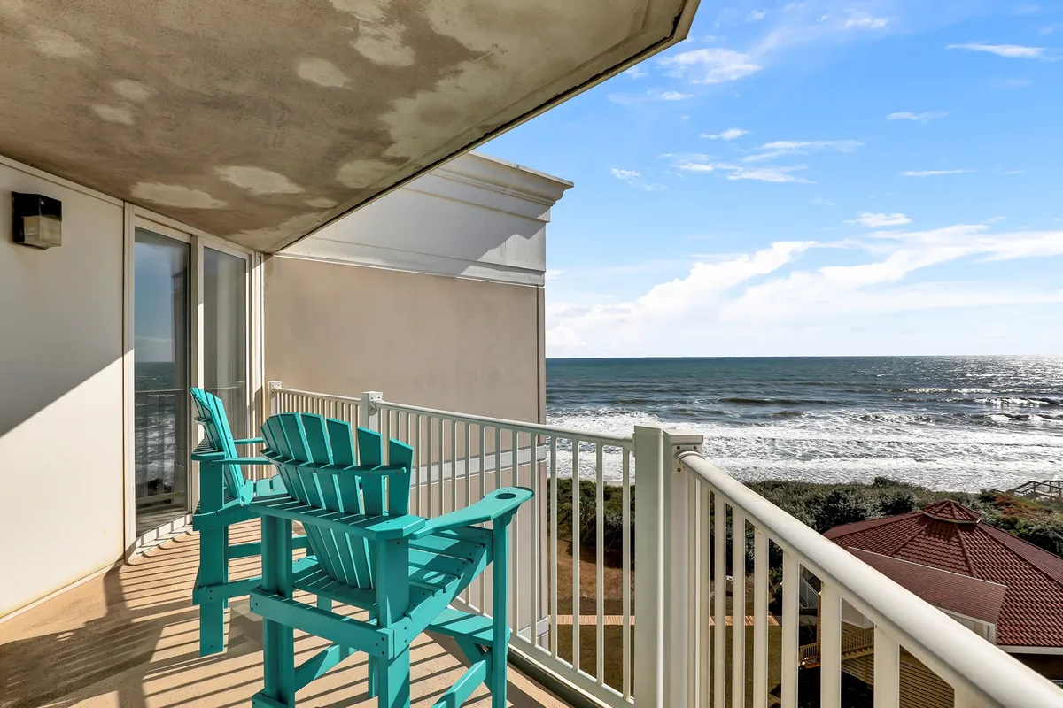 This image shows a tranquil balcony setup with turquoise chairs overlooking a mesmerizing ocean view. The railings frame an expanse of sea and sky, suggesting a peaceful spot for couples to relax, stargaze, or watch the sunset together.