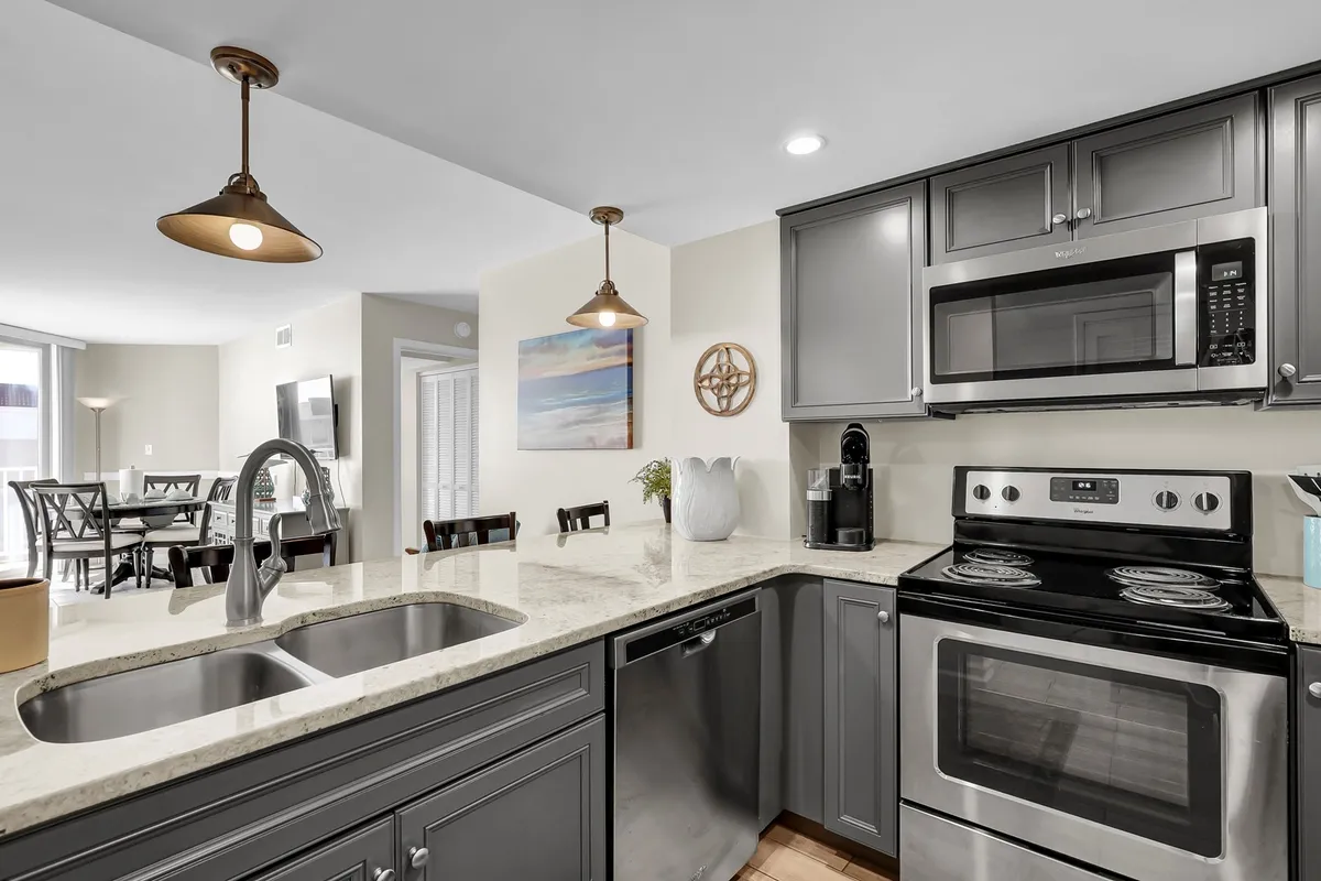 A modern kitchen featuring a striking granite countertop, stainless steel appliances, stylish pendant lighting, and a spacious kitchen island. The layout is open and airy, ideally suited for both cooking and entertaining.