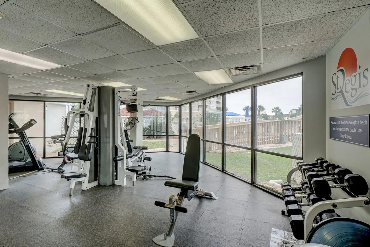A modern fitness area filled with exercise equipment and large windows that flood the room with natural light. The setting is energizing, with views to the outdoors and ample space for individual or group routines.